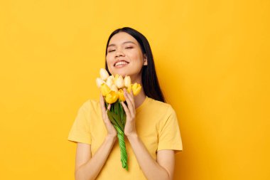 Asya görünümlü bir buket çiçekli kadın bahar eğlencesi modellik yapıyor.