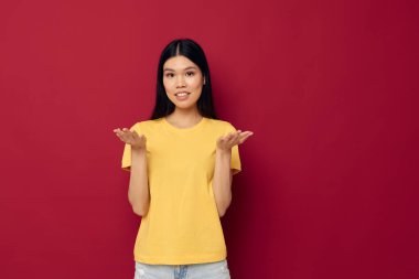 Çekici genç Asyalı kadın sarı günlük tişört gülüşü kırmızı arka plan pozu veriyor.