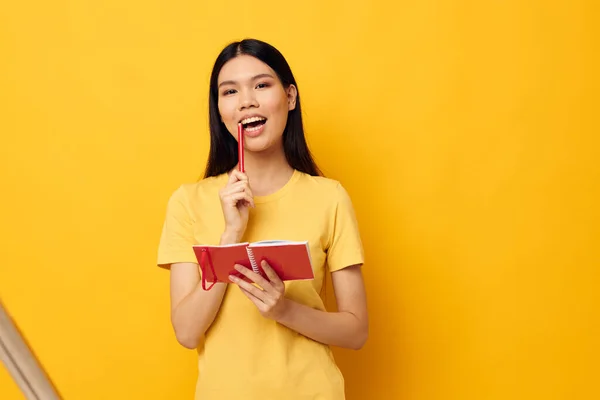 Jolie brune dans un t-shirt jaune carnet rouge modèle studio d'entraînement inchangé — Photo