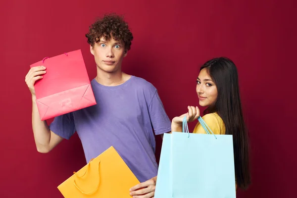 Νεαρό αγόρι και κορίτσι πολύχρωμες τσάντες ψώνια διασκέδαση απομονωμένη φόντο αναλλοίωτη — Φωτογραφία Αρχείου