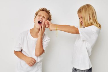 Beyaz tişörtlü iki çocuğun fotoğrafı bej arka planda duruyor.