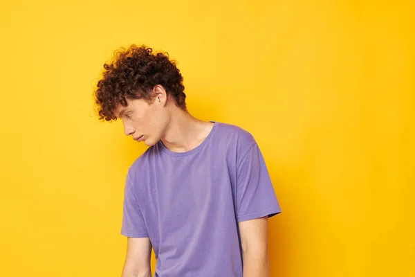 Хлопець з кучерявим волоссям у фіолетових футболках студія жовтий фон — стокове фото