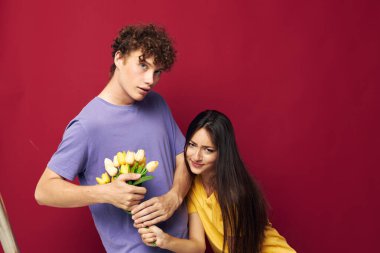 Genç bir erkek ve kız hediye olarak çiçek buketi. Değişmemiş bir arka plan.