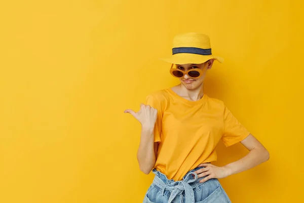 Photo pretty girl in sunglasses a yellow t-shirt and Hat summer style yellow background — Stockfoto