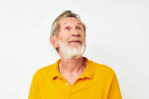 Foto de um velho aposentado com uma barba cinza emoção gestos mãos luz fundo — Fotografia de Stock