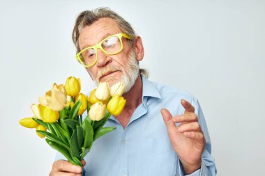 Emekli yaşlı bir adamın fotoğrafı. Bir buket çiçek. Hediye olarak hafif bir arka plan.