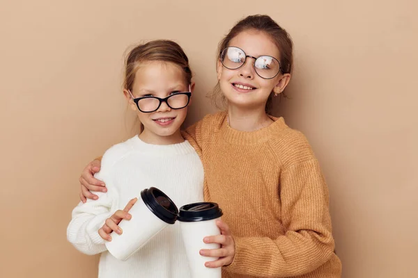 Twee kleine meisjes wegwerp bril poseren beige achtergrond — Stockfoto