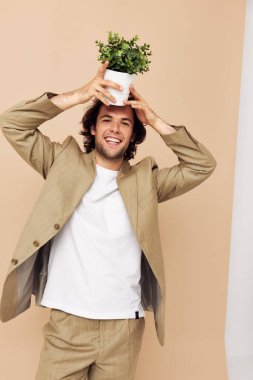 Elinde çiçek saksısı olan neşeli bir adam Klasik bej arka plan