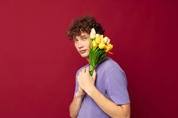 Lindo adolescente sosteniendo un ramo amarillo de flores púrpura camisetas aislado fondo inalterado — Foto de Stock