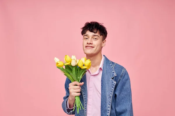 Portrét mladého muže v džínové bundě s kyticí květin dárek romantická dovolená beze změny — Stock fotografie