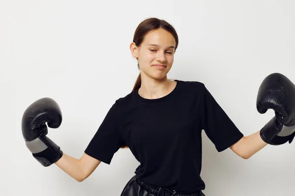 Jovem mulher bonita em luvas de boxe em calças pretas e um fundo de luz T-shirt — Fotografia de Stock