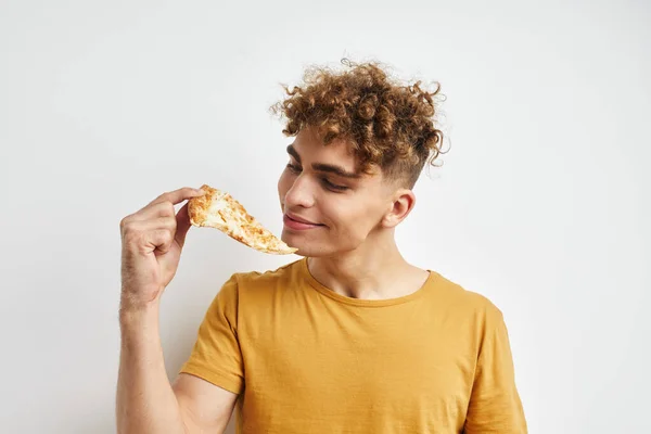Красивий молодий чоловік у жовтій футболці, що їсть піцу Стиль життя незмінний — стокове фото