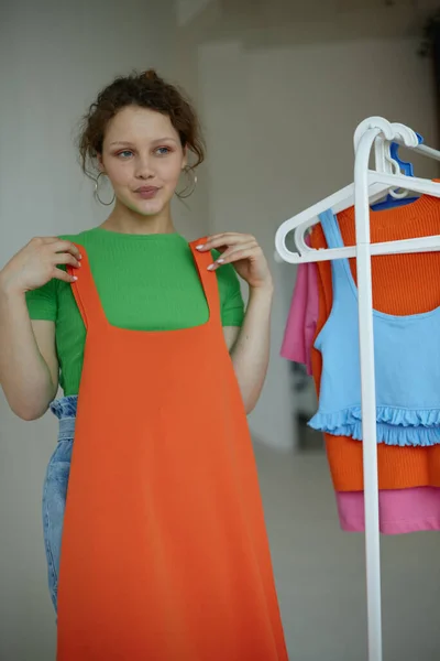 Chica divertida planchando ropa en un fondo de luz armario percha inalterada —  Fotos de Stock