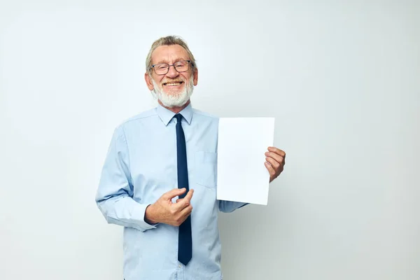 Portrait of happy senior man holding documents with a sheet of paper light background