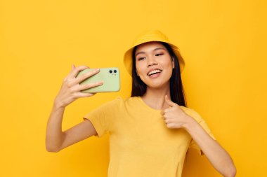 Elinde telefon tutan kadın yaşam teknolojisi pozu veriyor sarı arka plan değiştirilmemiş