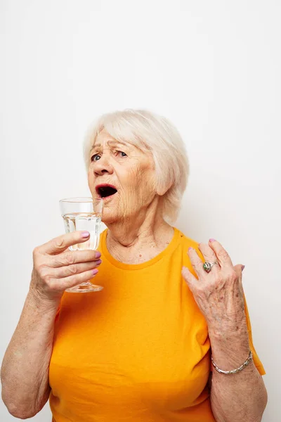 Sourire femme âgée tenant un verre d'eau santé lumière arrière-plan — Photo
