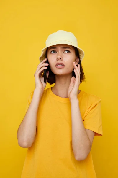 Bella ragazza in un cappello giallo stile giovanile casual parlando sul telefono sfondo isolato — Foto Stock
