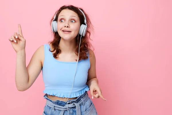 Fröhliches Mädchen mit Kopfhörern im Jugendstil posiert vor unverändertem rosa Hintergrund — Stockfoto