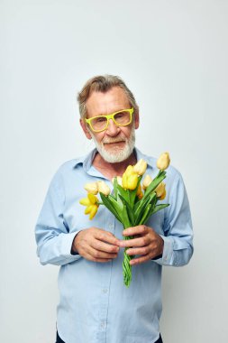 Yaşlı adam sarı çiçek buketi açık arkaplan pozu veriyor.