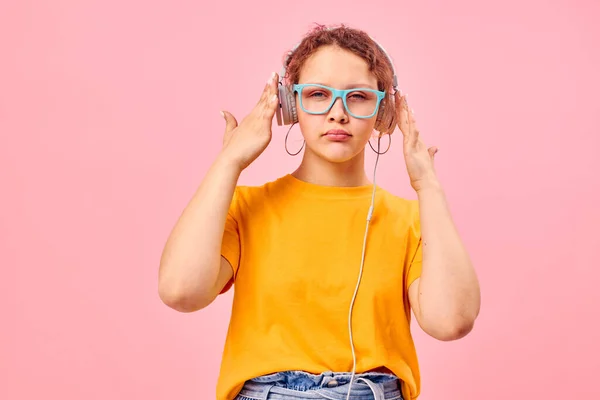 Αστείο κορίτσι κίτρινο t-shirt ακουστικά ψυχαγωγία μουσική διασκέδαση ροζ φόντο αναλλοίωτη — Φωτογραφία Αρχείου