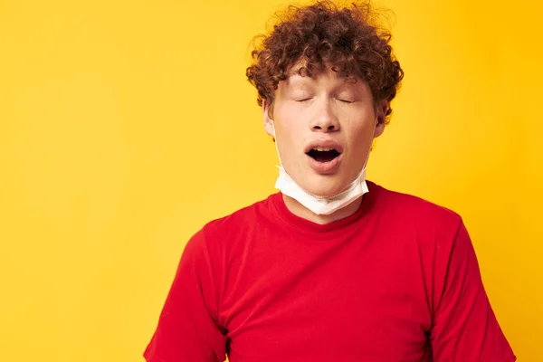 Ung lockig man i en röd t-shirt medicinsk mask skydd Livsstil oförändrad — Stockfoto