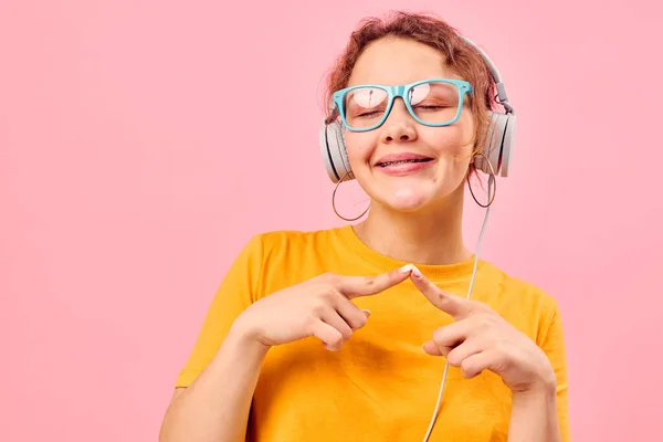 Hübsches Mädchen gelbes T-Shirt Kopfhörer Unterhaltung Musik Spaß rosa Hintergrund unverändert — Stockfoto