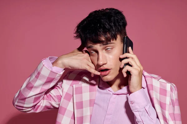 Un joven con un teléfono en la mano chaqueta rosa de moda estilo elegante aislado fondo inalterado — Foto de Stock