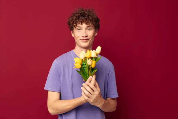 Дивний хлопець тримає жовтий букет квітів фіолетові футболки ізольований фон незмінний — стокове фото