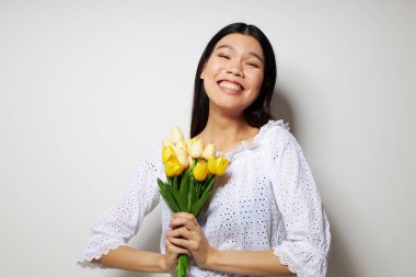 Beyaz gömlekli, Asyalı bir kadın. Çiçekler. Stüdyo modeli gibi poz veriyor.