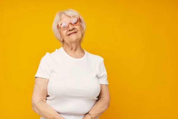 Mujer de edad avanzada en una camiseta blanca lleva gafas de fondo aislado — Foto de Stock