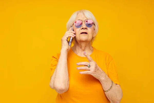 Sorridente mulher idosa estilo de vida feliz em camisetas amarelas com telefone close-up emoções — Fotografia de Stock