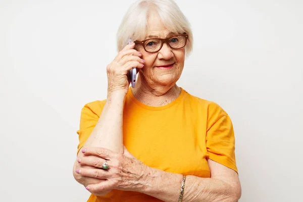 Foto de una anciana jubilada en una camiseta amarilla posando la comunicación por teléfono vista recortada — Foto de Stock