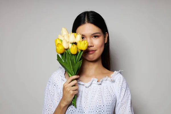 흰색 셔츠 꽃에 아시아의 모습을 하고 있는 여자가 아무런 변화 없이 밝은 배경을 드러내고 있다 — 스톡 사진