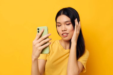 Elinde telefon olan bir kadın özçekim sarı arkaplanı değiştirilemez.