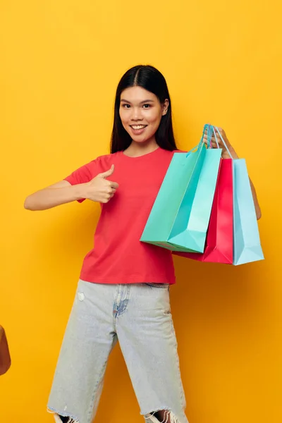 Mooie brunette met kleurrijke tassen poseren winkelen plezier gele achtergrond ongewijzigd — Stockfoto