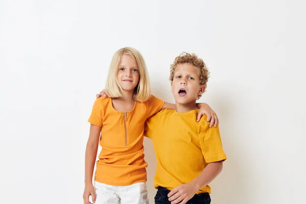 Chlapec a dívka ve žlutých tričkách stojí vedle sebe na lehkém pozadí pózují — Stock fotografie