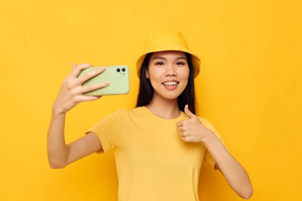 변경되지 않은 노란색 배경으로 핸드폰을 들고 있는 여성 — 스톡 사진