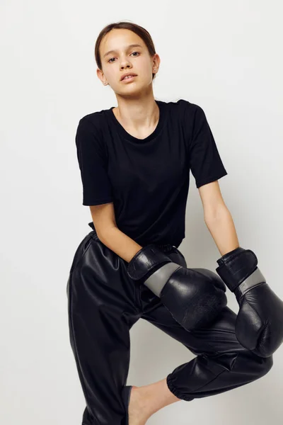 Hermosa chica en guantes de boxeo en pantalones negros y una camiseta estilo de vida inalterable — Foto de Stock