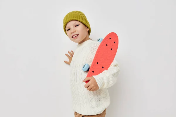 Μικρό κορίτσι με καπέλα με ένα skateboard στα χέρια τους φως φόντο — Φωτογραφία Αρχείου