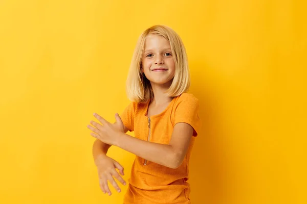 Kind Mädchen in einem gelben T-Shirt Lächeln posiert Studio Farbhintergrund unverändert — Stockfoto