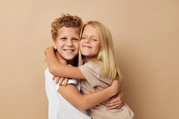 Menino e menina em t-shirts abraços bege fundo amizade — Fotografia de Stock