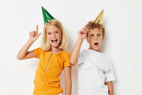 Dos niños alegres posando emociones vacaciones coloridas gorras fondo de luz —  Fotos de Stock