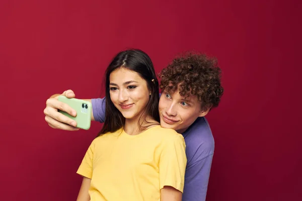 Homme et femme en T-shirts colorés avec un fond isolé téléphone — Photo