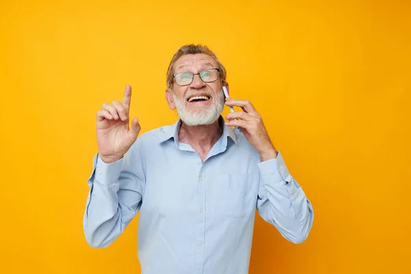 Photo d'un vieil homme à la retraite parlant au téléphone posant un fond jaune rapproché — Photo