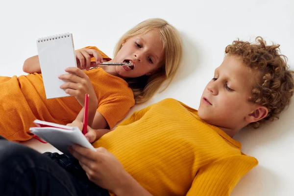 Cheerful children lie on the floor with notepads and pencils childhood lifestyle unaltered — Stockfoto
