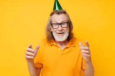 Kafasında şapkası olan sarı tişörtlü yaşlı bir adam. Eğlenceli tek renkli bir fotoğraf.