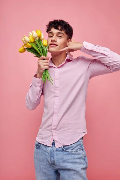 Молодий чоловік в рожевій сорочці з букетом квітів жестикулює руками ізольований фон незмінний — стокове фото