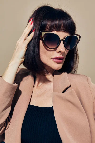 Retrato de una mujer en gafas de sol traje de pelo corto gesto con las manos fondo claro — Foto de Stock
