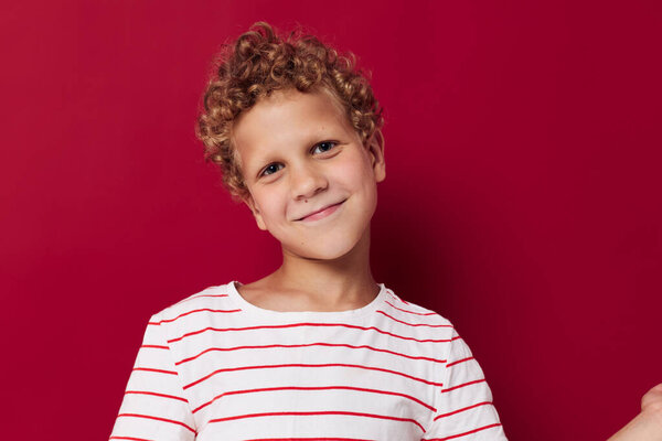 Веселый мальчик в полосатой футболке с улыбкой на красном фоне