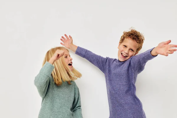 Симпатичные стильные дети в разноцветных свитерах позируют для веселого светлого фона — стоковое фото
